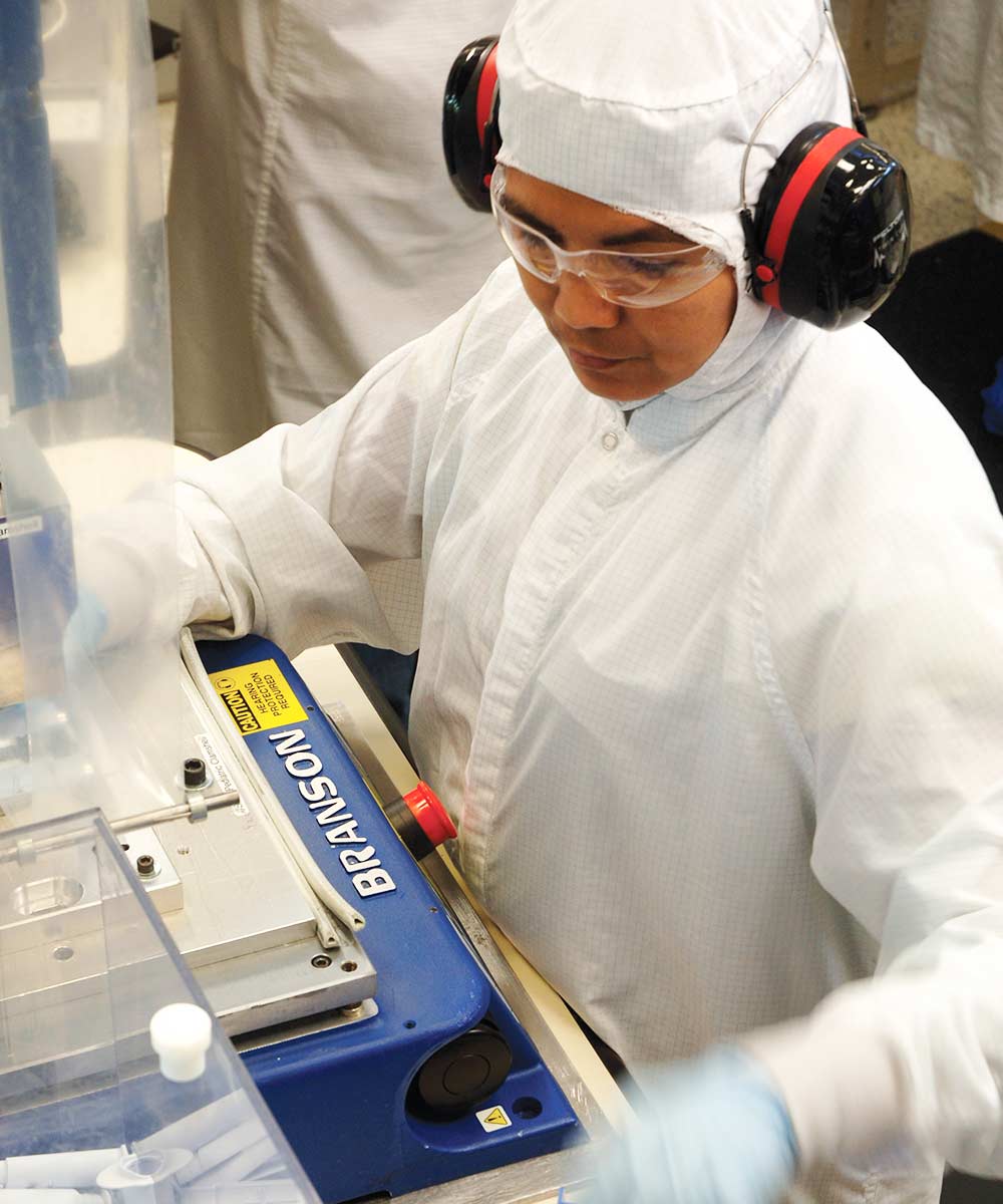 person in white suit working on manufacturing machine