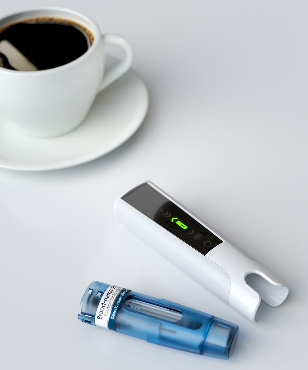 smart autoinjector on table with a cup of coffee
