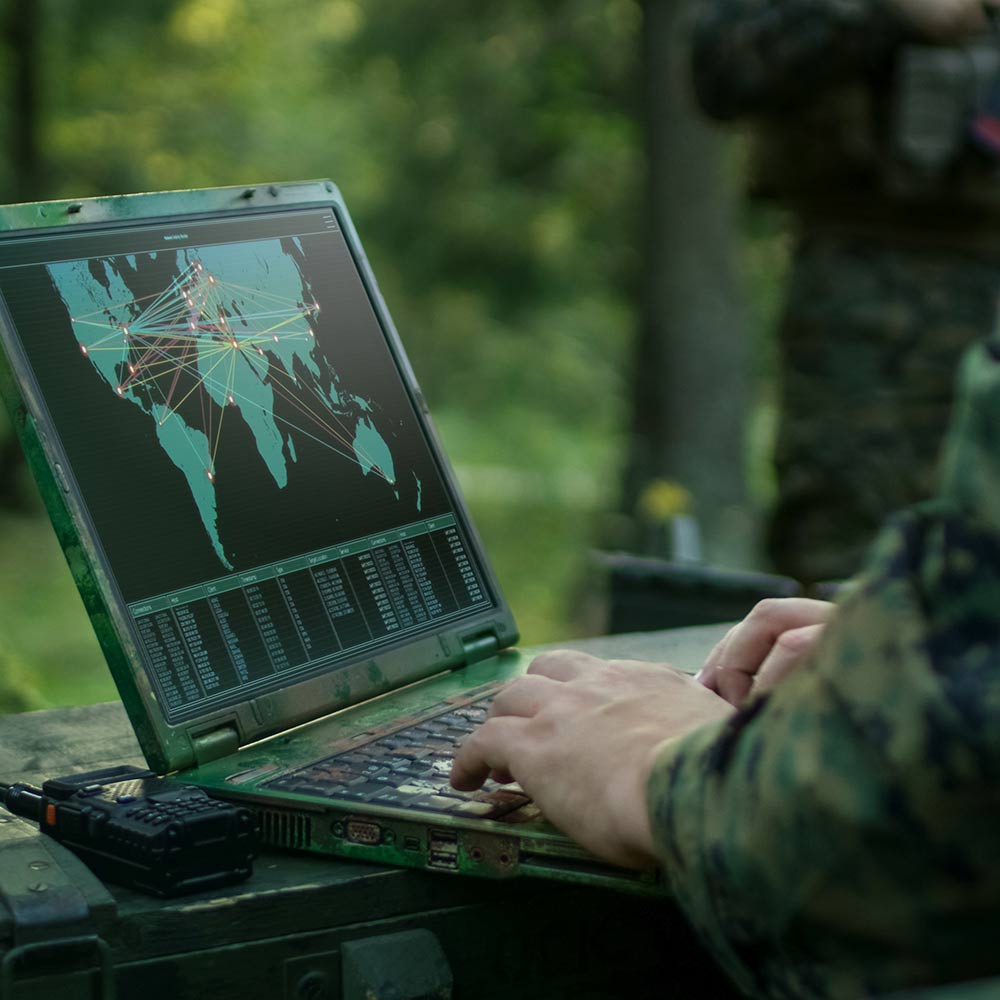 person in army uniform typing on computer with map of the world